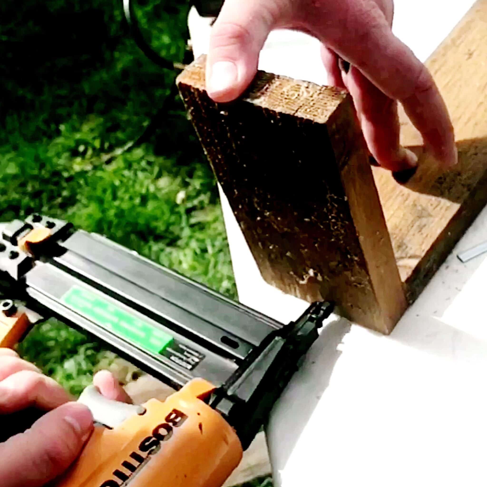 Man using nail gun to attach 2 wood piece making a diy wood planter
