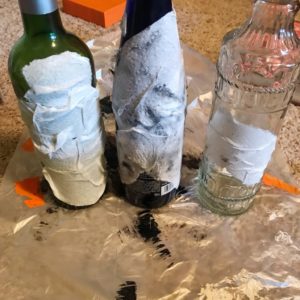 3 wine bottles covered in paper towels and mod podge